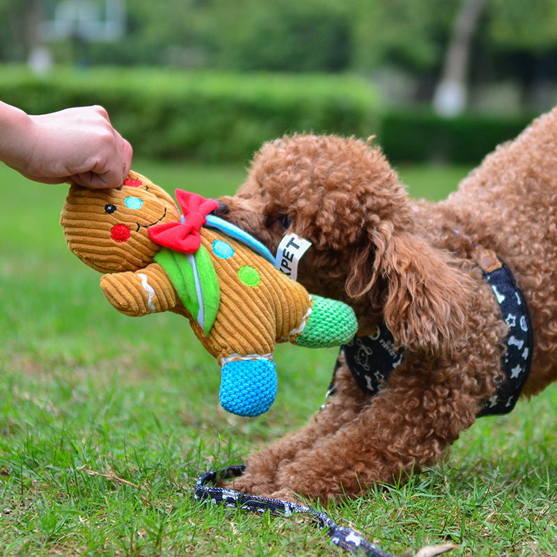 Dog playing with a gingerbread man plush toy